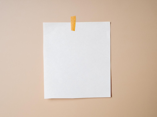 Blank sheet of paper taped on a beige background