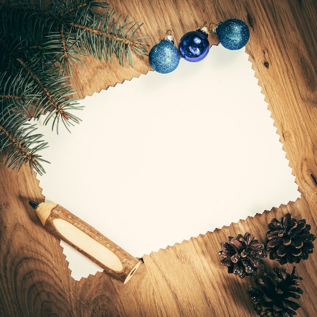 Blank sheet of paper on the wooden floor with a pencil and Christmas decorations