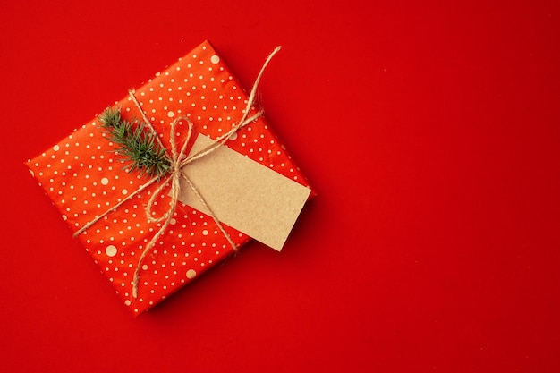 紙の空白のシートと赤い背景の上のクリスマスのお祝いのための包装されたプレゼント