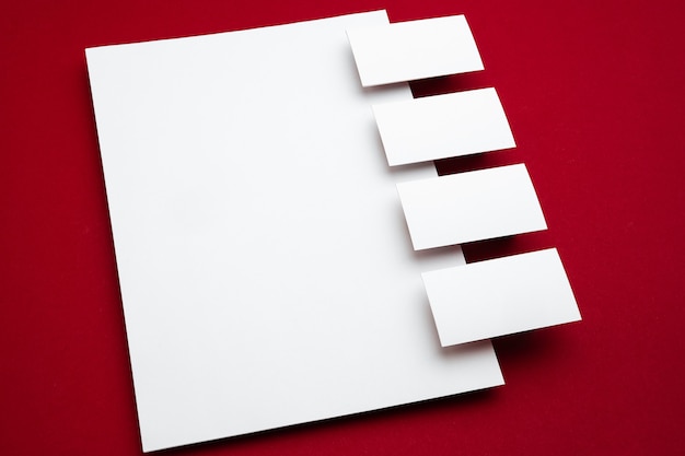 Blank sheets floating above red background, creative. White cards in line. Office styled, modern mockup for advertising. Blank white copyspace for design, business and finance concept.