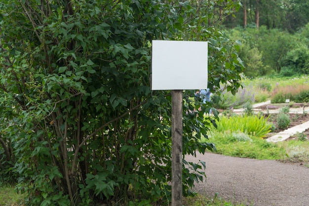 Segno in bianco nel parco su uno sfondo di alberi