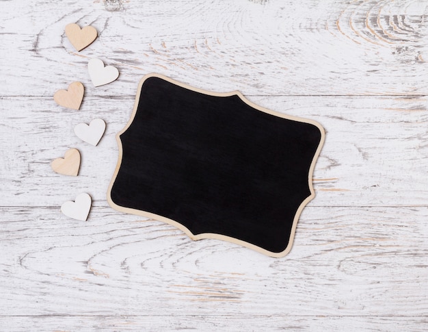 Blank sign with wooden hearts on rustic table