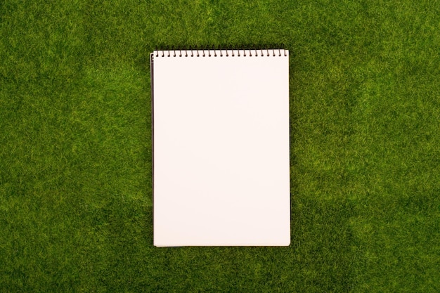 Blank spiral note pad on the grass meadow Mock up