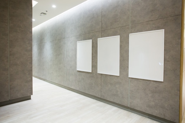 Blank square posters on concrete wall in empty hall