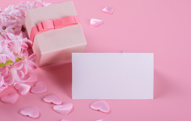 Mockup di carta regalo di cancelleria vuota, biglietto di ringraziamento, biglietto da visita su sfondo rosa con fiori di giacinto e cuori rosa