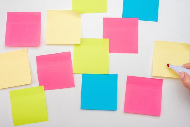 Blank sticker notes on white background hand with red marker
ready to write mockup sticky note paper empty sheets for notes on
white bulletin board colored sticky notes