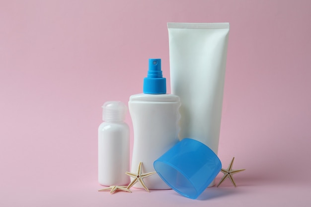 Blank sunscreens and starfishes on pink isolated background