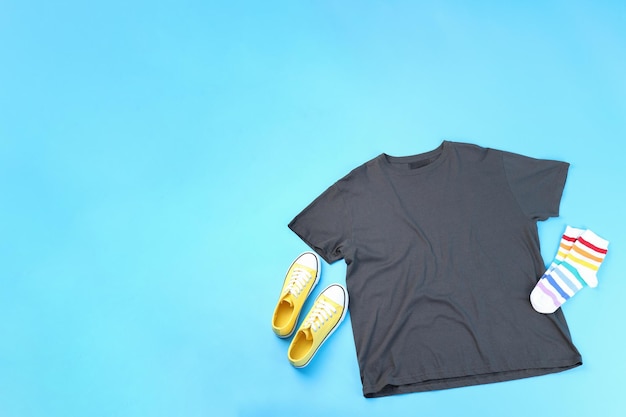 Blank t-shirt, sneakers and socks on blue background