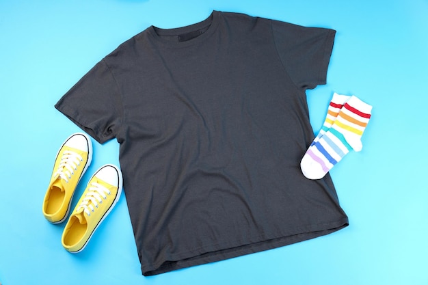 Blank t-shirt, sneakers and socks on blue background