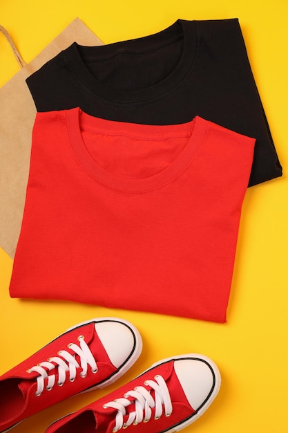 Blank t-shirts, sneakers and bag on yellow background