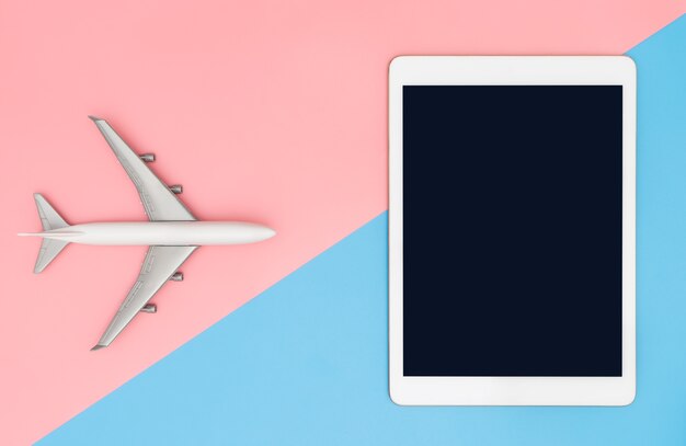 Blank tablet screen with toy plane for travel concept