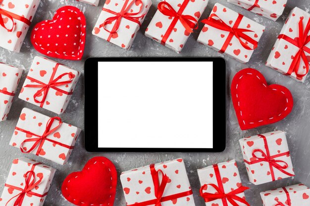 blank tablet surrounded by gift boxes with hearts wrapping paper and textile hearts