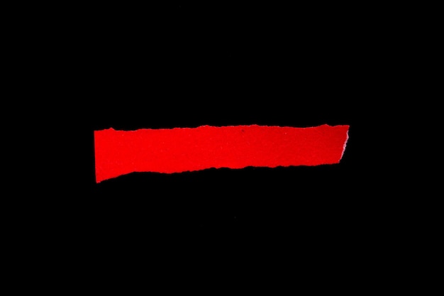 Blank torn paper isolated on black background. Top view of red paper piece with copy space.