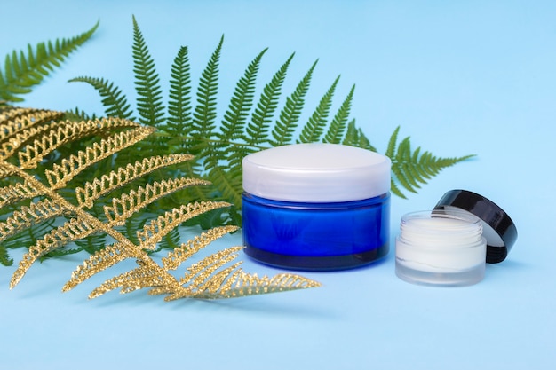 Blank two jars of cream with natural, golden fern palm leaves. 