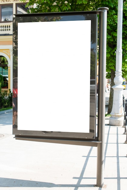 Blank vertical street billboard stand with city background.