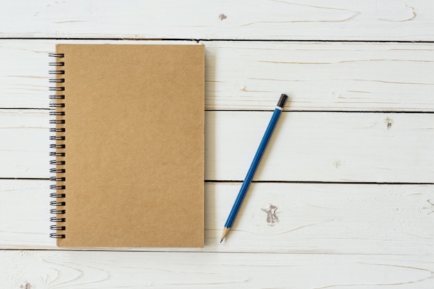 Blank vintage paper notebook with pencil on wood table