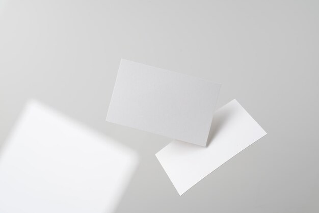 Photo blank visiting cards in mid-air against gray background