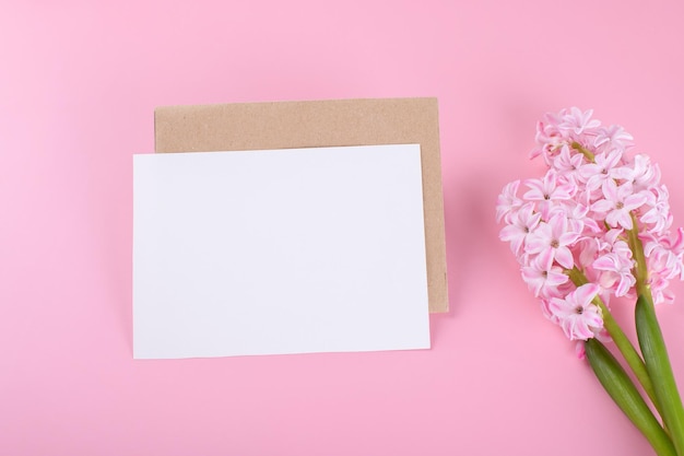 Blank wedding invitation card mockup with envelope on pink background with hyacinth flowers