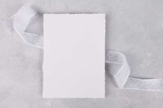 Blank wedding invitation stationery card mockup on grey stone table background with white ribbon, 5x7