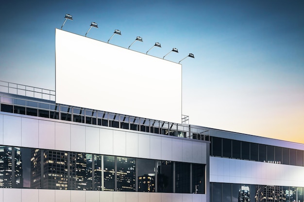건물 창문 3D 렌더링에 스포트라이트와 야간 도시 고층빌딩이 반사된 비즈니스 센터 옥상에 있는 빈 흰색 광고판