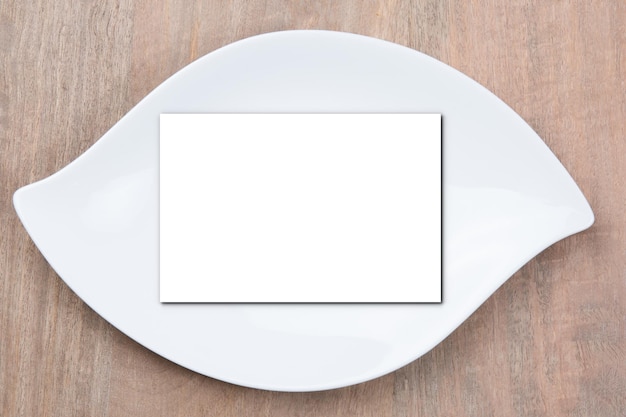 Photo blank white business card mockup in plate over white table background