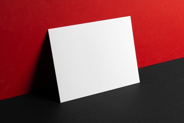 Blank white business cards on red and black paper background, copy space