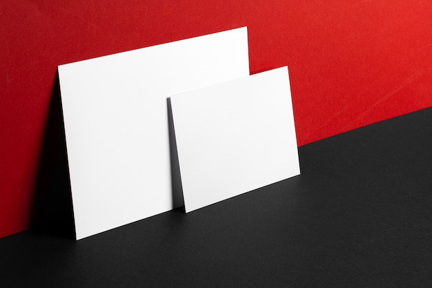 Blank white business cards on red and black paper background, copy space