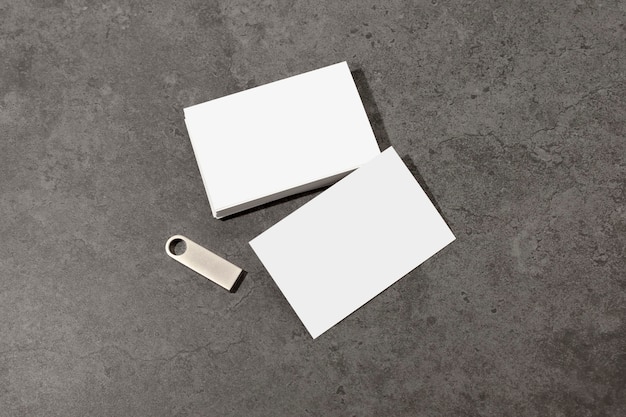Blank white business cards on table, with blank metallic usb\
stick. mockup for branding identity. possibility to show both sides\
of card. template for graphic designers. free space, copy\
space.