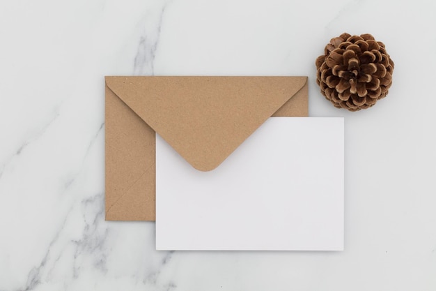 Blank white card with kraft brown paper envelope on marble background