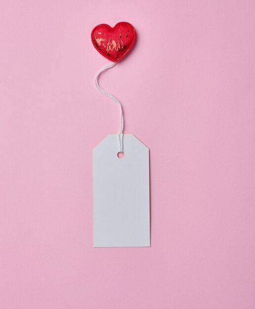 Blank white cardboard tag on white rope pink background