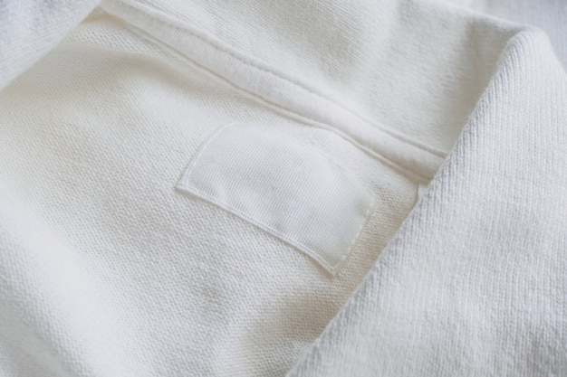 Пустая белая этикетка одежды на фоне новой хлопковой рубашки
