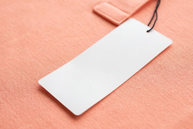 Blank white clothes tag label on pink fabric texture background