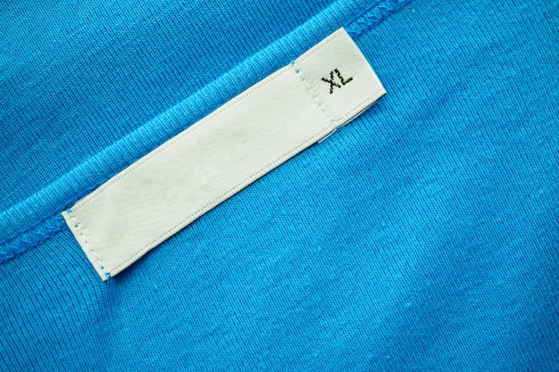 Blank white clothes tag label with xl size on new blue shirt