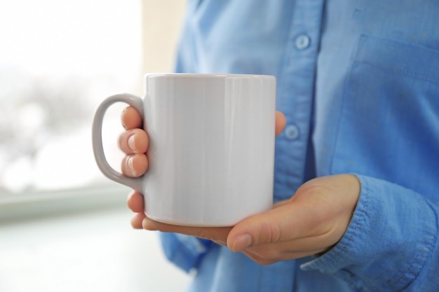 Blank white cup in hands closeup