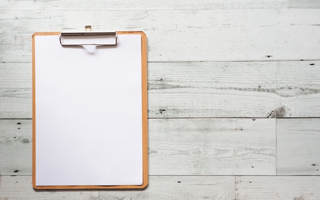 Photo blank white document on wood clipboard on white wood table top view space,business concept