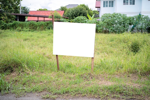 Photo blank white empty mockup template of a real estate sign at front of a lot of vacant lan