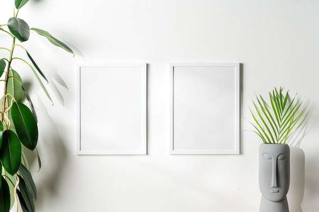 Photo blank white frames and houseplant against white wall