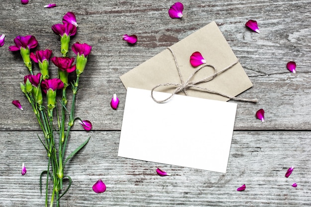 Фото Пустая белая открытка и конверт с фиолетовыми цветами гвоздики