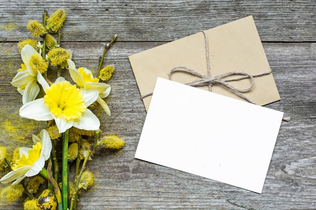 Cartolina d'auguri e busta bianche in bianco con i fiori del narciso e