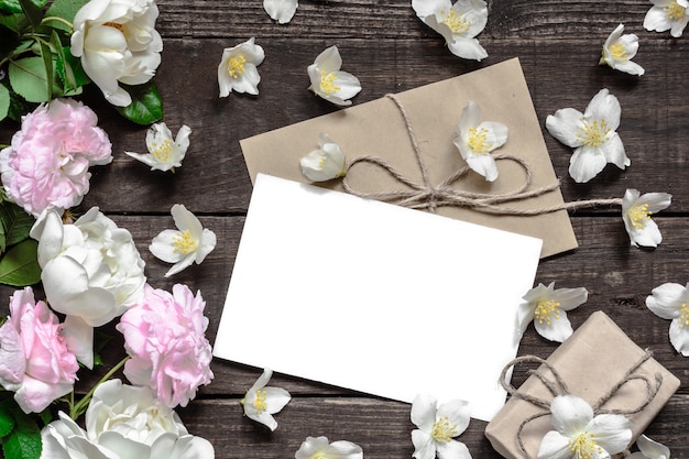 Foto biglietto di auguri bianco bianco con rose rosa e bianche in cornice fatta di fiori di gelsomino con scatola regalo