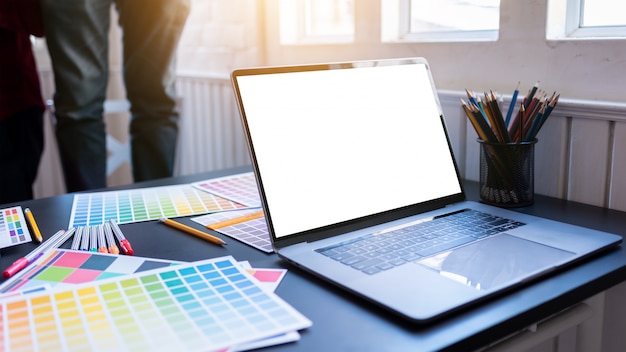 Blank white laptop screen of graphic designers put on desk table in co-working 