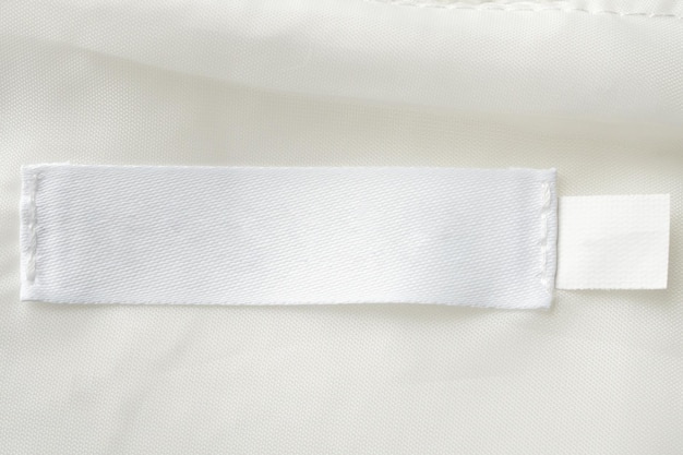 Blank white laundry care clothes label on fabric texture background