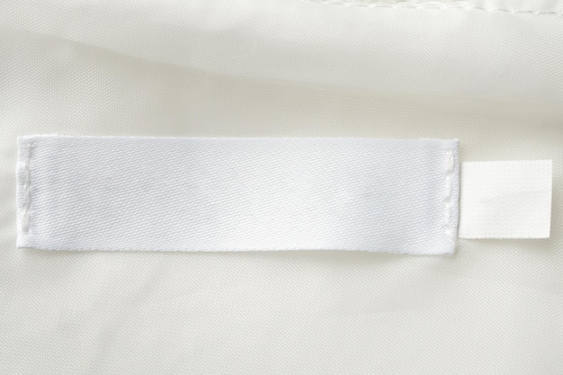 Foto etichetta bianca di abbigliamento per la lavanderia su sfondo di consistenza tessile