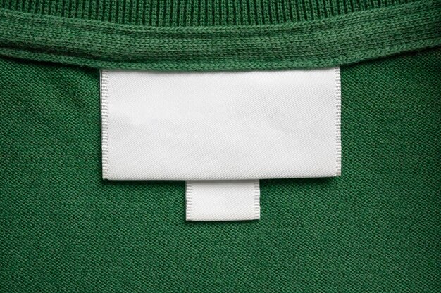 Photo blank white laundry care clothes label on green shirt fabric texture background