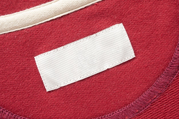 Blank white laundry care clothes label on red fabric texture background