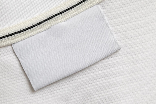 Blank white laundry care clothes label on white shirt fabric texture background