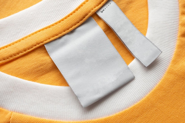 Etichetta bianca vuota per vestiti per la cura del bucato su sfondo di struttura del tessuto giallo