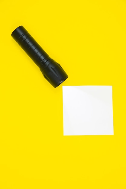 Foto adesivo bianco vuoto per la lista delle cose da fare con torcia nera. ricerca di informazioni su internet. close up di promemoria carta su sfondo giallo. copia spazio. minimalismo, originale e creativo.