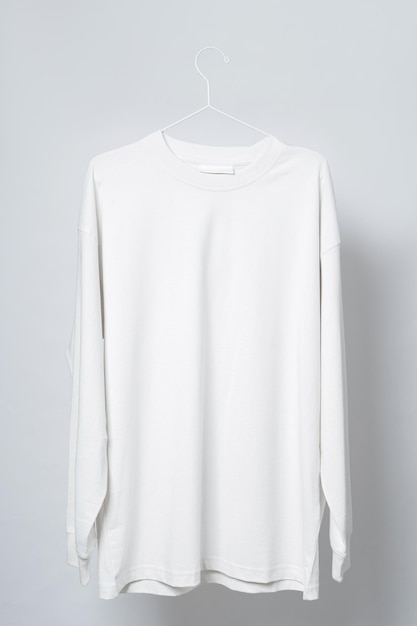 Blank white long-sleeved t-shirt hanging on the thin metallic hanger against light gray background