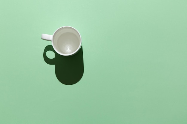 Photo blank white mug in hard light on a pastel green background top view flat lay